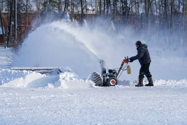 Man blowing snow with a snow blower—how to drain gas from Ariens snowblower