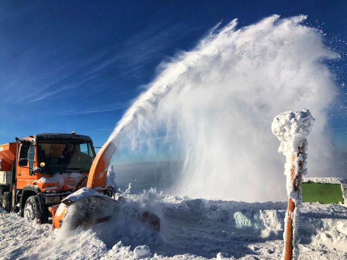 A snow blower is spraying snow onto the ground photo