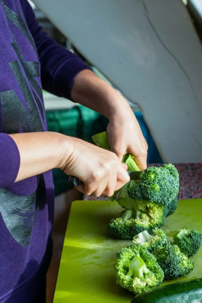 Person Slicing Green Broccoli Are Black Spots on Broccoli Stems Safe to Eat
